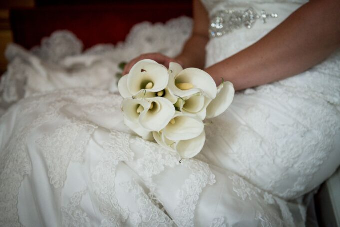 Eine Braut hält einen Strauß Calla-Lilien in der Hand.