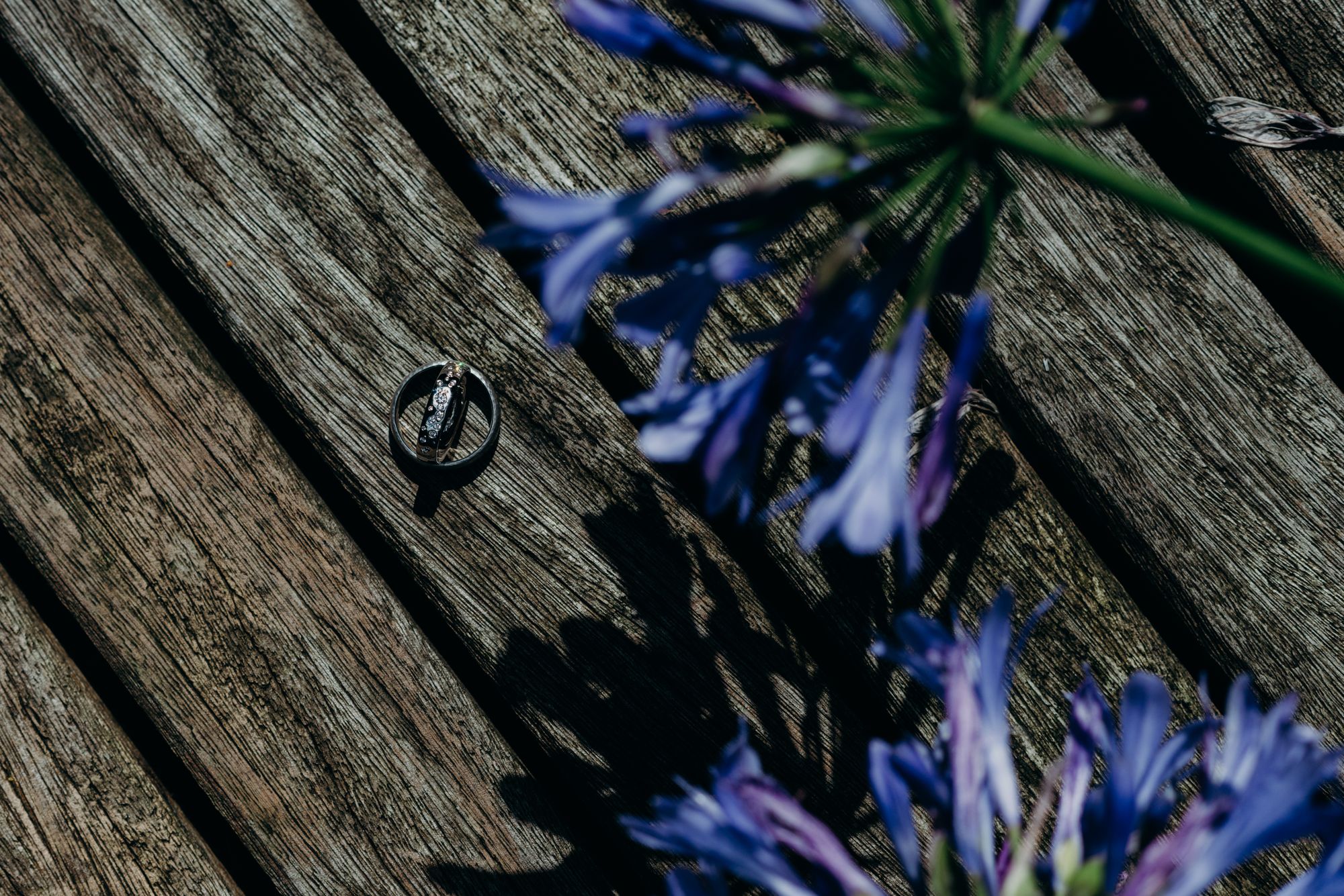 Ein Ehering auf einem Holzdeck mit blauen Blumen.