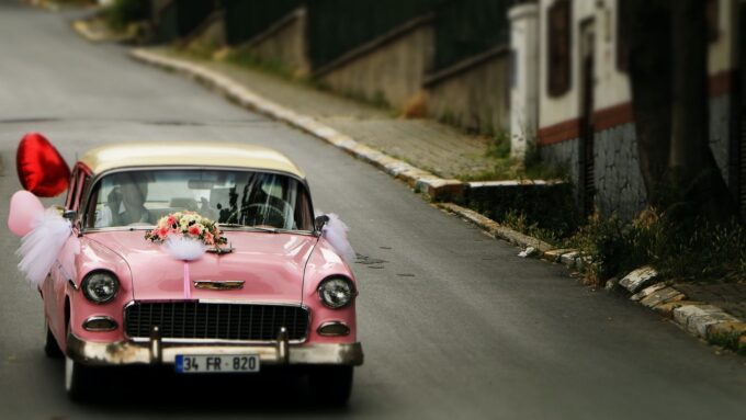 Ein rosa Auto fährt eine Straße entlang.