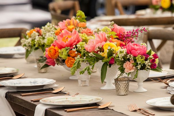 Ein langer Tisch mit bunten Blumen und Tellern.