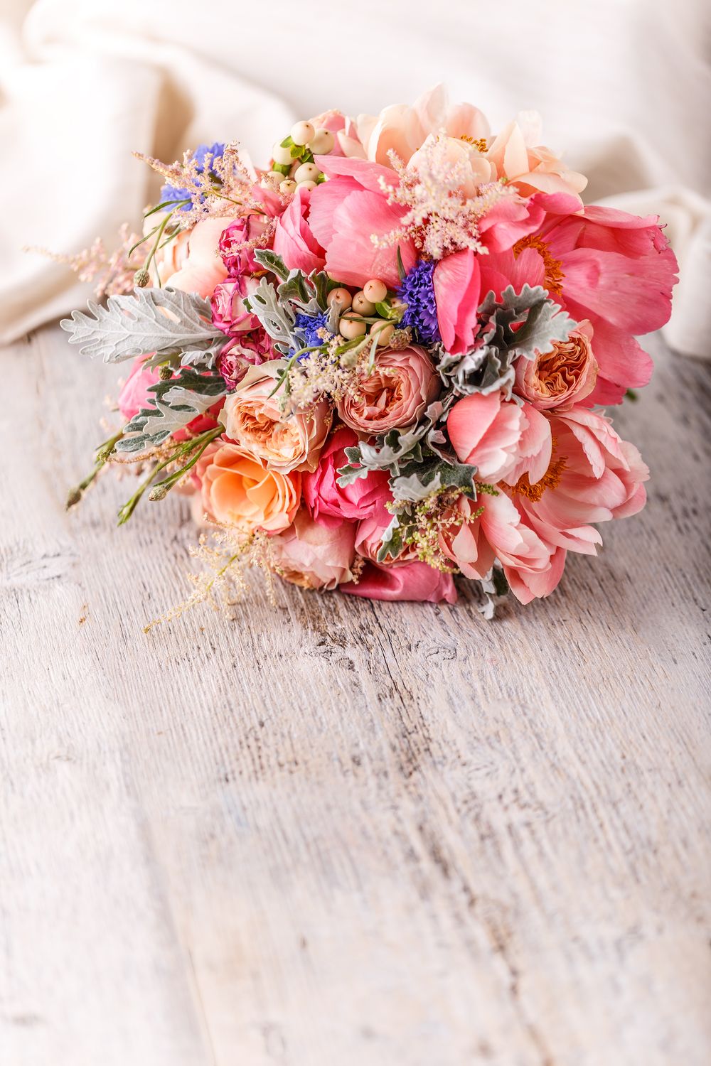 Ein Strauß rosa und orangefarbener Blumen auf einem Holztisch.