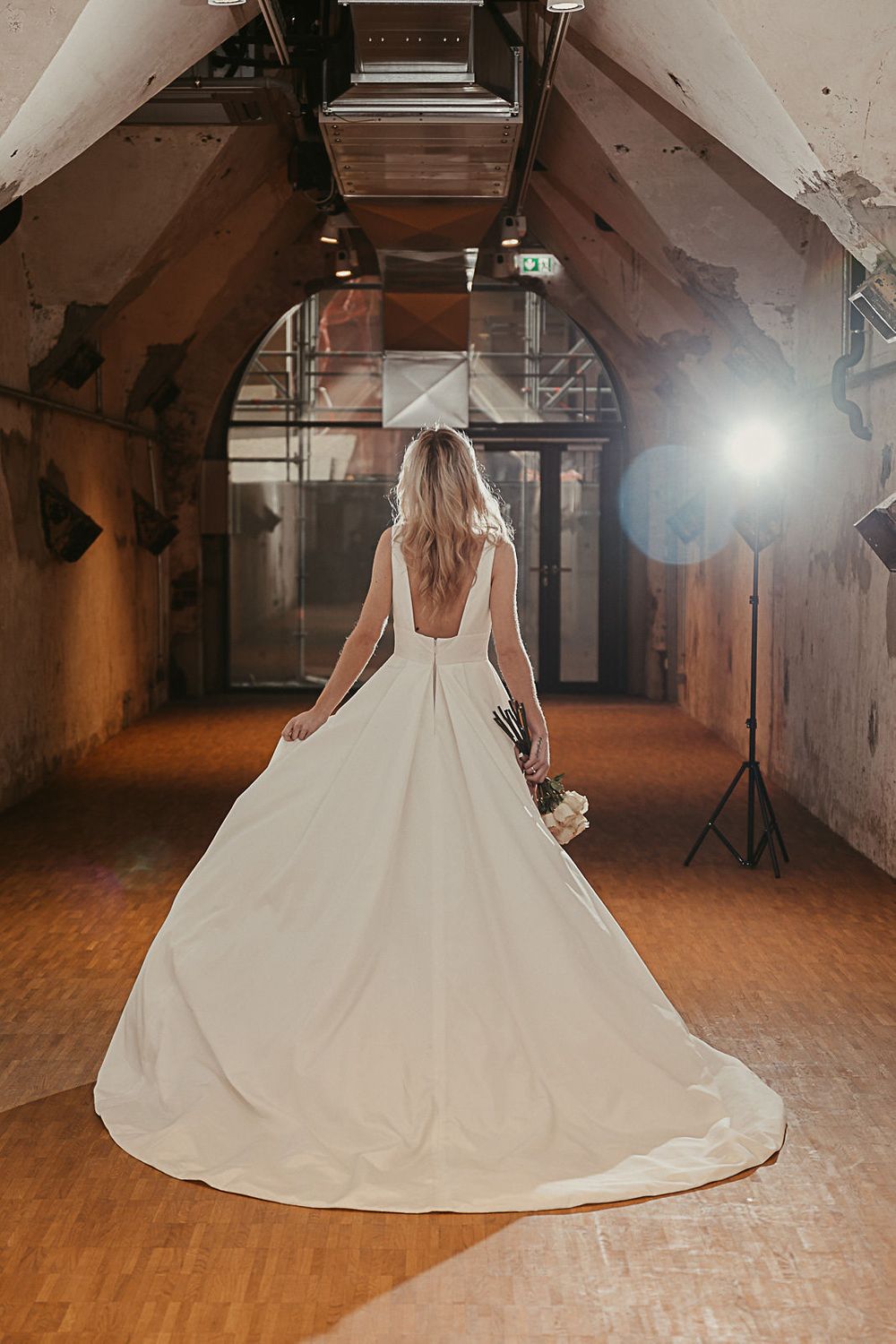 Eine Braut in einem Hochzeitskleid steht in einem dunklen Raum.