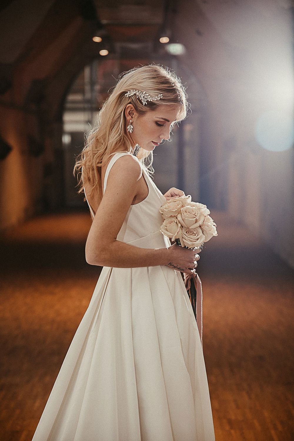 Eine Braut in einem weißen Hochzeitskleid hält einen Blumenstrauß.