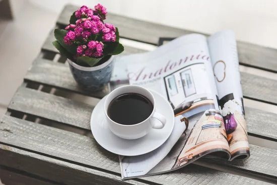 Eine Tasse Kaffee und eine Zeitschrift auf einem Holztisch.