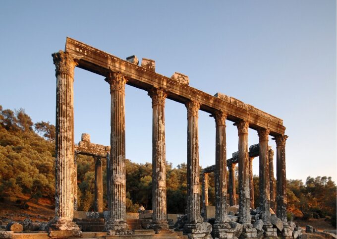 Die Ruinen eines Tempels mit Säulen im Hintergrund.