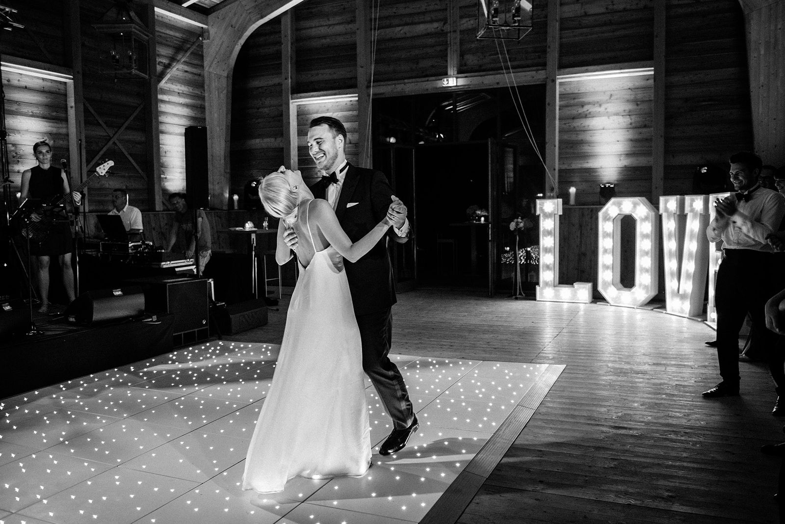 Ein Brautpaar tanzt vor einem beleuchteten Liebesschild.