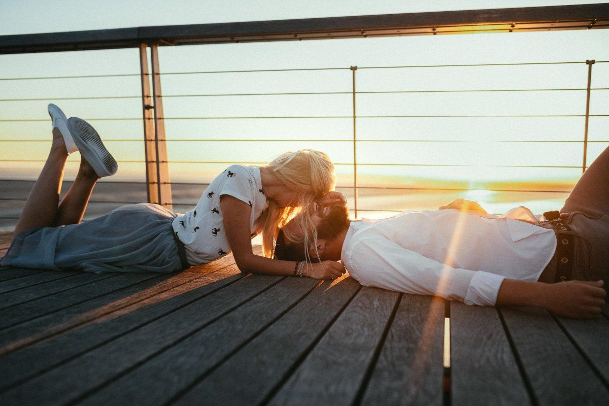 Ein Mann und eine Frau liegen bei Sonnenuntergang auf einer Promenade.