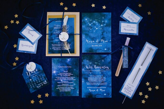 Ein Satz blau-goldener Hochzeitseinladungen mit Sternen darauf.