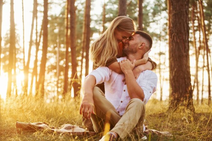 Ein Mann und eine Frau umarmen sich bei Sonnenuntergang im Wald.