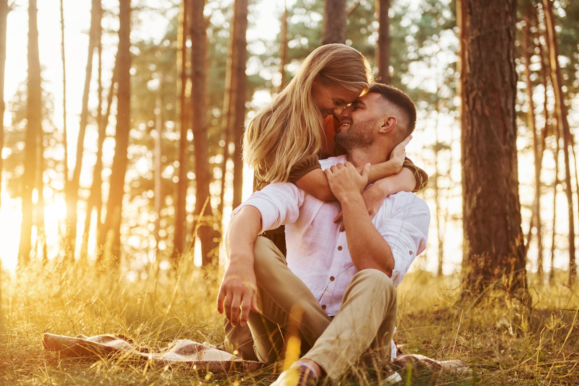 Ein Mann und eine Frau umarmen sich bei Sonnenuntergang im Wald.