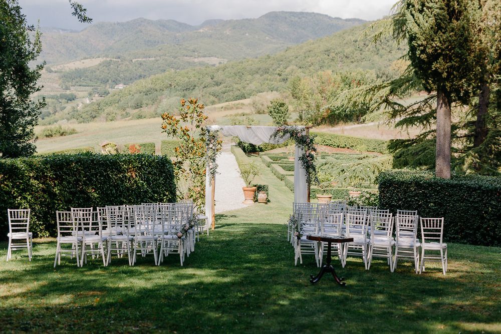 Eine Hochzeitszeremonie im Freien in einem Weinberg mit Bergen im Hintergrund.