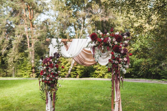 Ein mit Blumen geschmückter Hochzeitsbogen in einem Park.