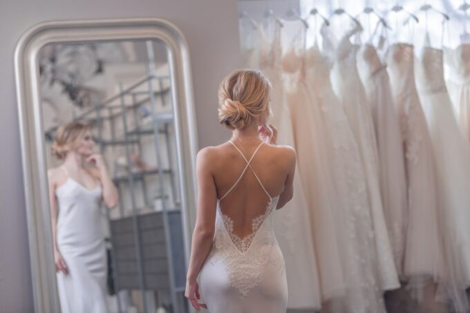 Eine Frau in einem Hochzeitskleid, die sich im Spiegel betrachtet.