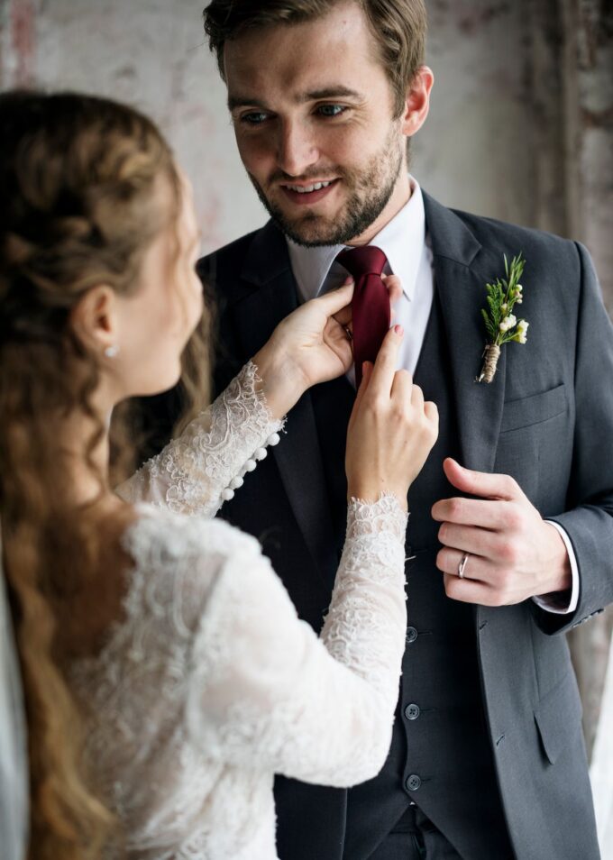 Eine Braut und ein Bräutigam passen sich gegenseitig ihre Krawatten an.