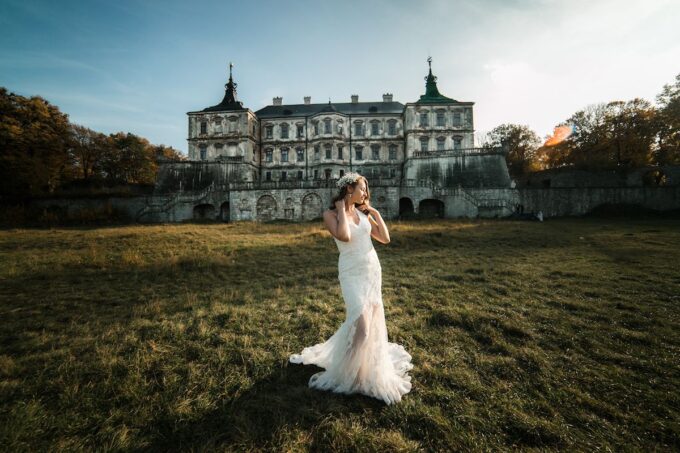 Eine Braut in einem weißen Kleid steht vor einem alten Schloss.