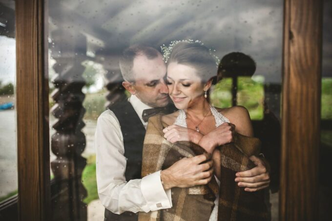 Ein Brautpaar umarmt sich vor einer Glastür.