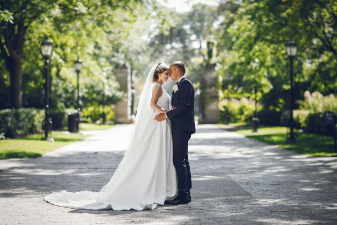 Eine Braut und ein Bräutigam küssen sich in einem Park.