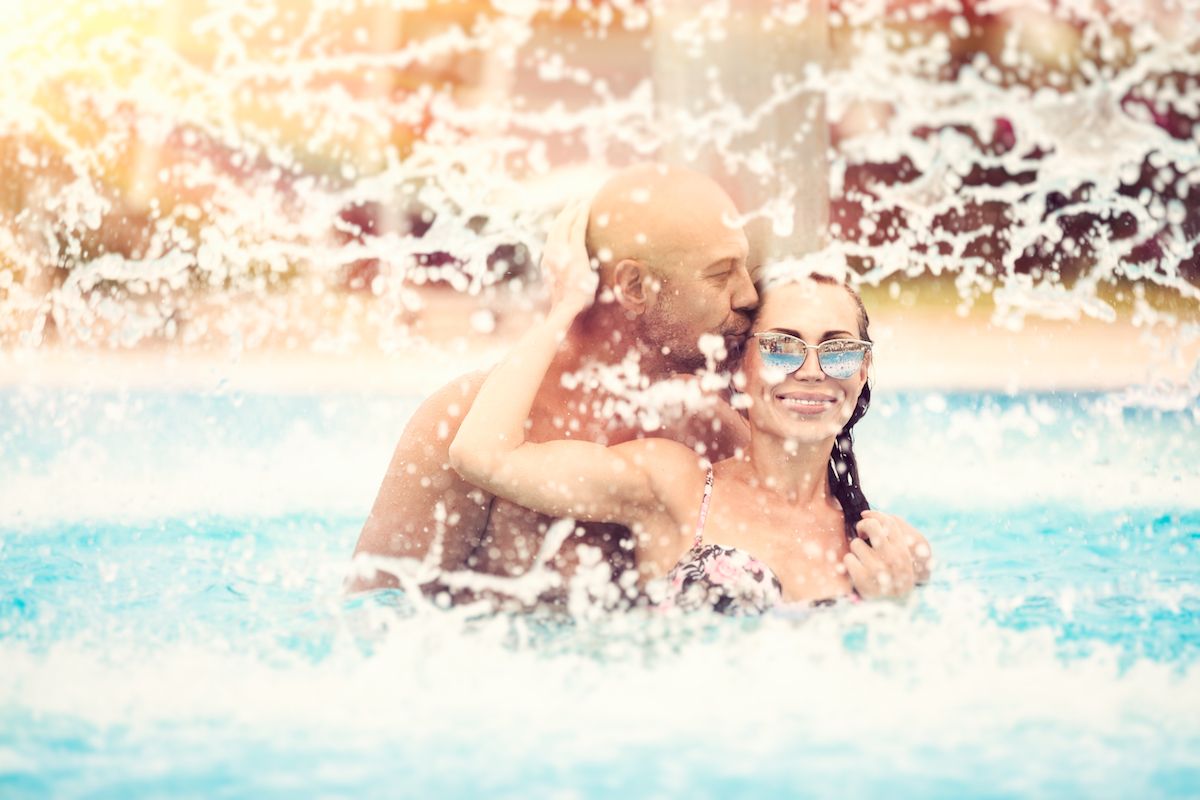 Ein Mann und eine Frau küssen sich in einem Schwimmbad.