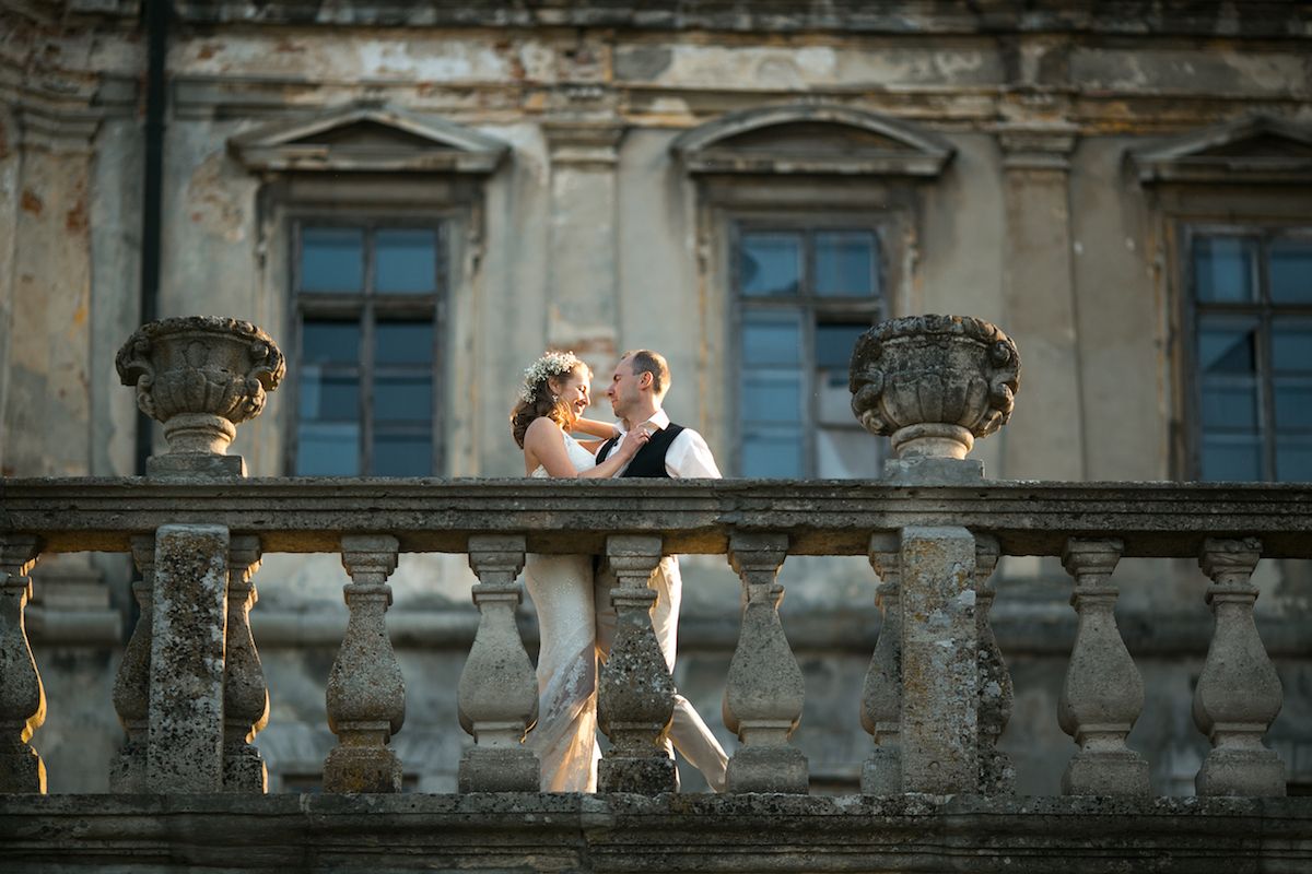 Eine Braut und ein Bräutigam stehen auf dem Balkon eines alten Gebäudes.