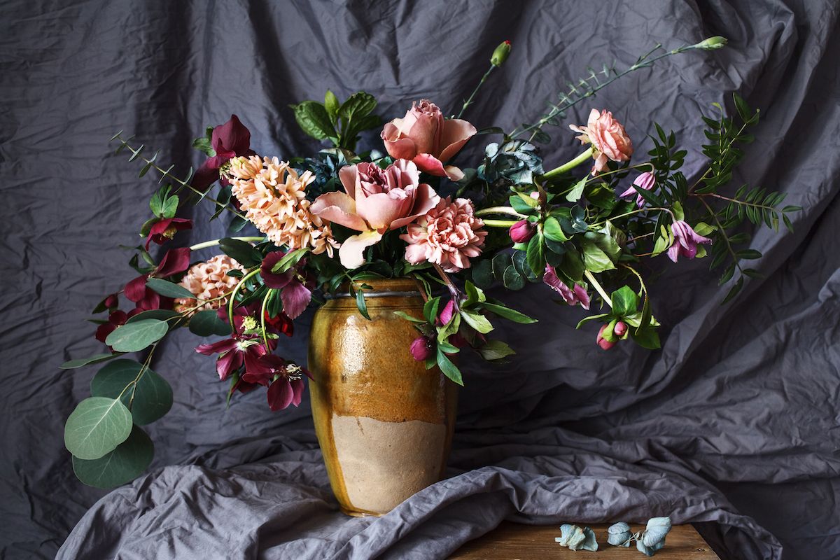 Eine goldene Vase, gefüllt mit Blumen und Grün.
