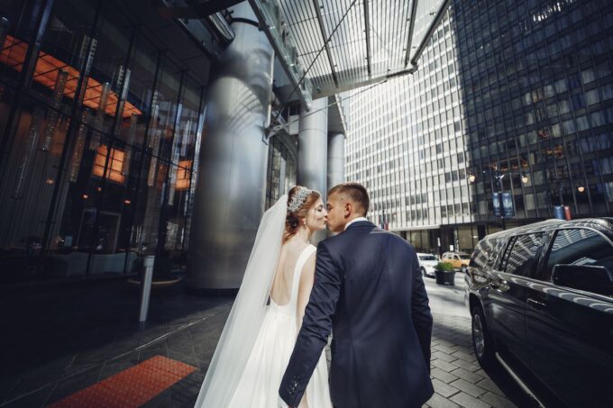 Eine Braut und ein Bräutigam küssen sich vor einem Gebäude.