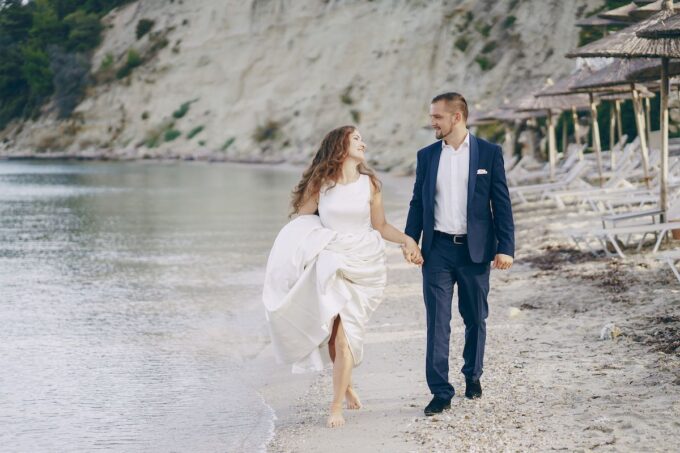 Eine Braut und ein Bräutigam, die am Strand spazieren gehen.