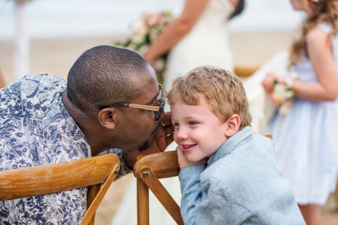 Ein Mann küsst einen kleinen Jungen am Strand.