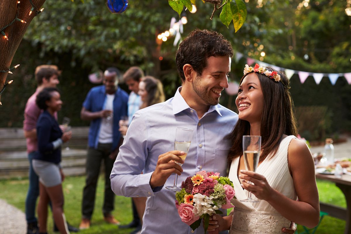 Eine Braut und ein Bräutigam trinken Champagner auf einer Hinterhofparty.