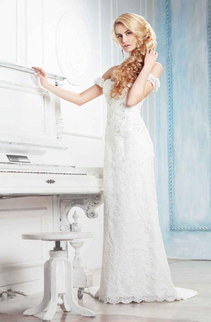 Eine schöne Frau in einem weißen Hochzeitskleid posiert neben einem Klavier.