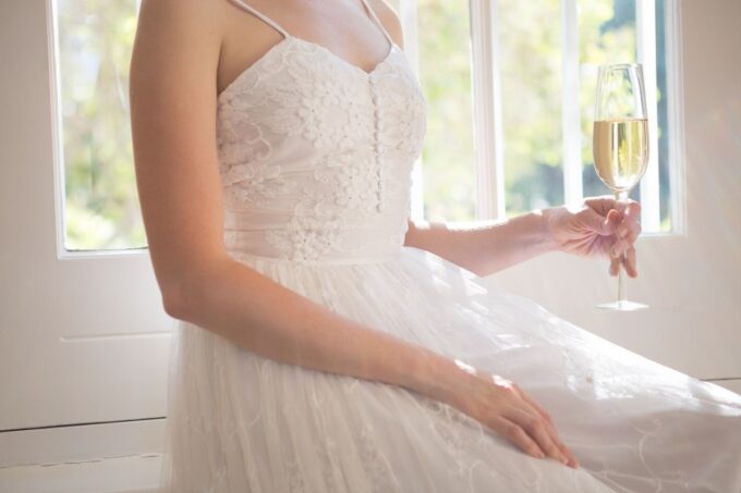 Eine Frau in einem weißen Kleid hält ein Glas Champagner.