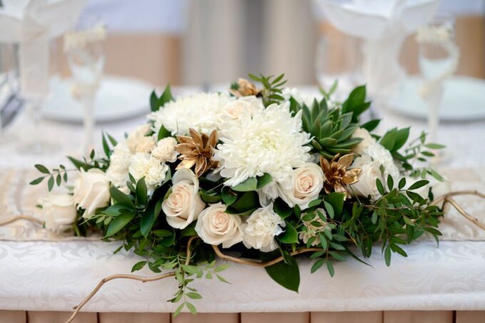 Ein Hochzeitstisch mit weißen Blumen und Grün.