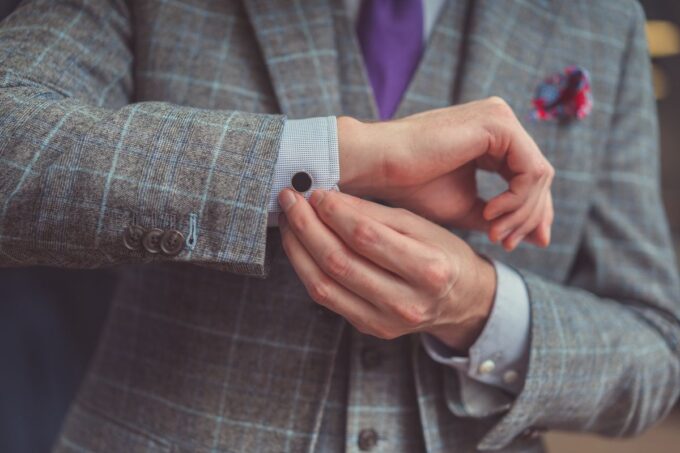 Ein Mann in einem Anzug passt seine Manschettenknöpfe an.