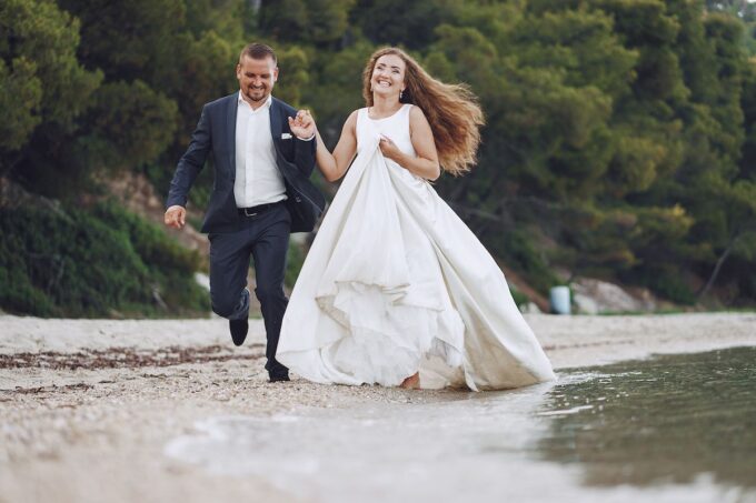 Eine Braut und ein Bräutigam laufen am Strand.