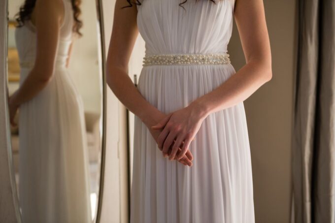 Eine Braut in einem weißen Kleid steht vor einem Spiegel.