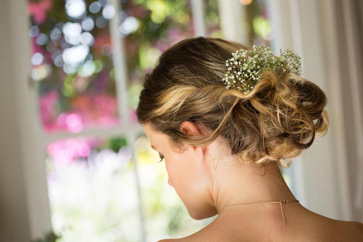 Eine Braut mit einer Schleierkrautblume im Haar.