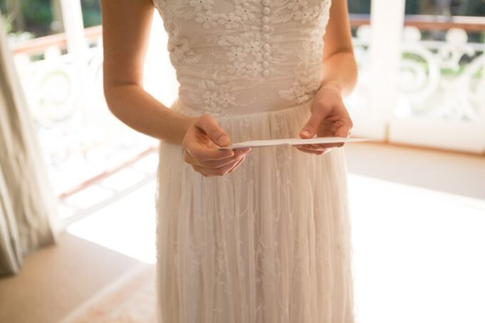 Eine Braut in einem weißen Kleid hält eine Hochzeitskarte.