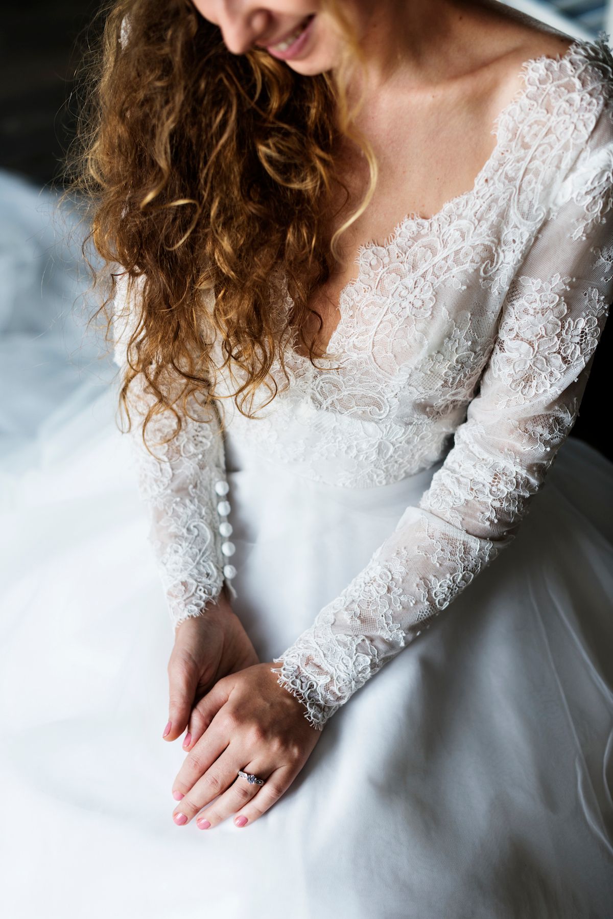 Eine Braut im Hochzeitskleid sitzt auf einem Bett.