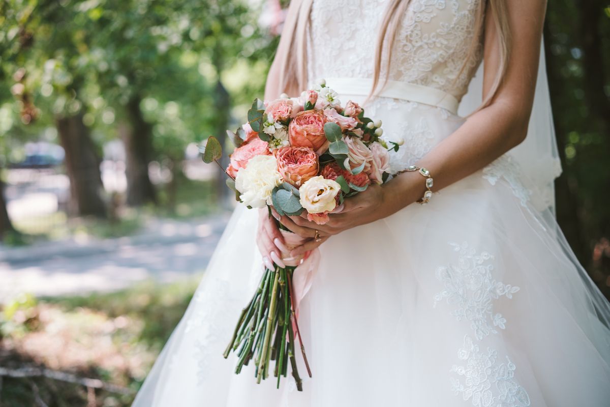 Eine Braut in einem Hochzeitskleid hält einen Blumenstrauß.