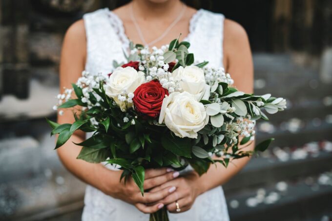Eine Braut hält einen Strauß weißer und roter Rosen.