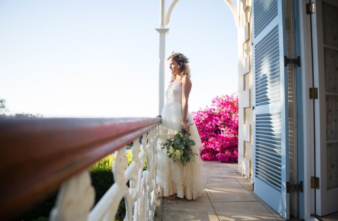 Eine Braut in einem Hochzeitskleid steht auf einem Balkon.