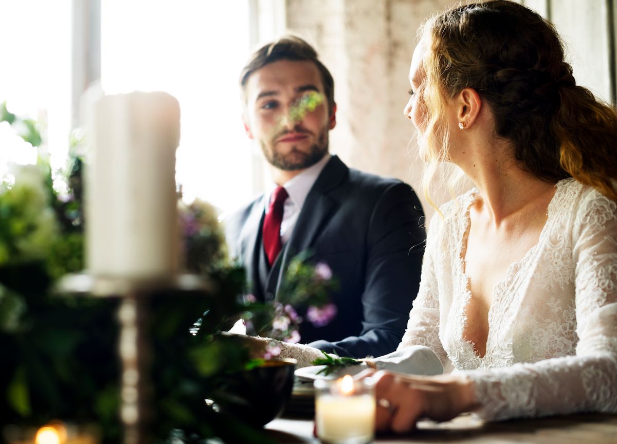 Eine Braut und ein Bräutigam schauen sich an einem Hochzeitstisch an.