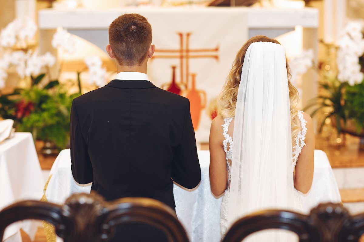 Eine Braut und ein Bräutigam schauen sich in einer Kirche an.