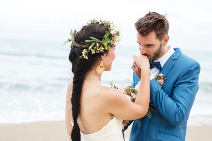 Eine Braut und ein Bräutigam küssen sich am Strand.