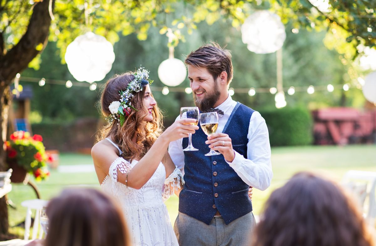 Eine Braut und ein Bräutigam stoßen bei einer Hochzeit im Freien an.