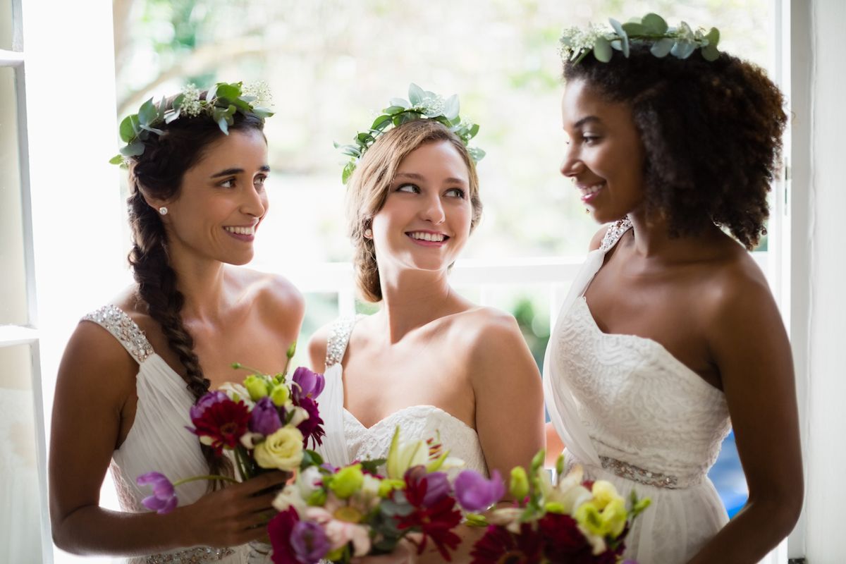 Drei Brautjungfern lächeln mit ihren Blumensträußen.