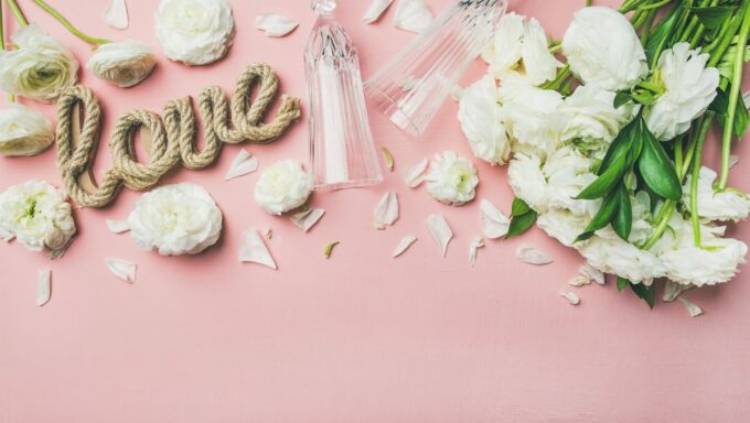 Weiße Blumen mit dem Wort Liebe auf rosa Hintergrund.