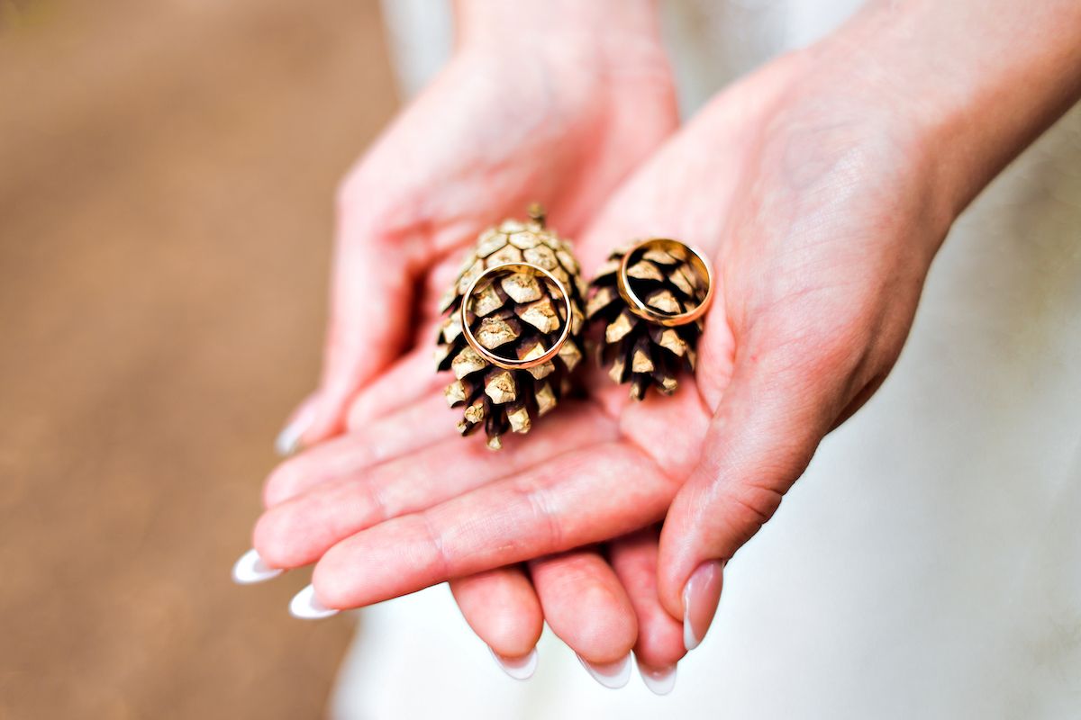 Eine Braut hält zwei Tannenzapfen in ihren Händen.