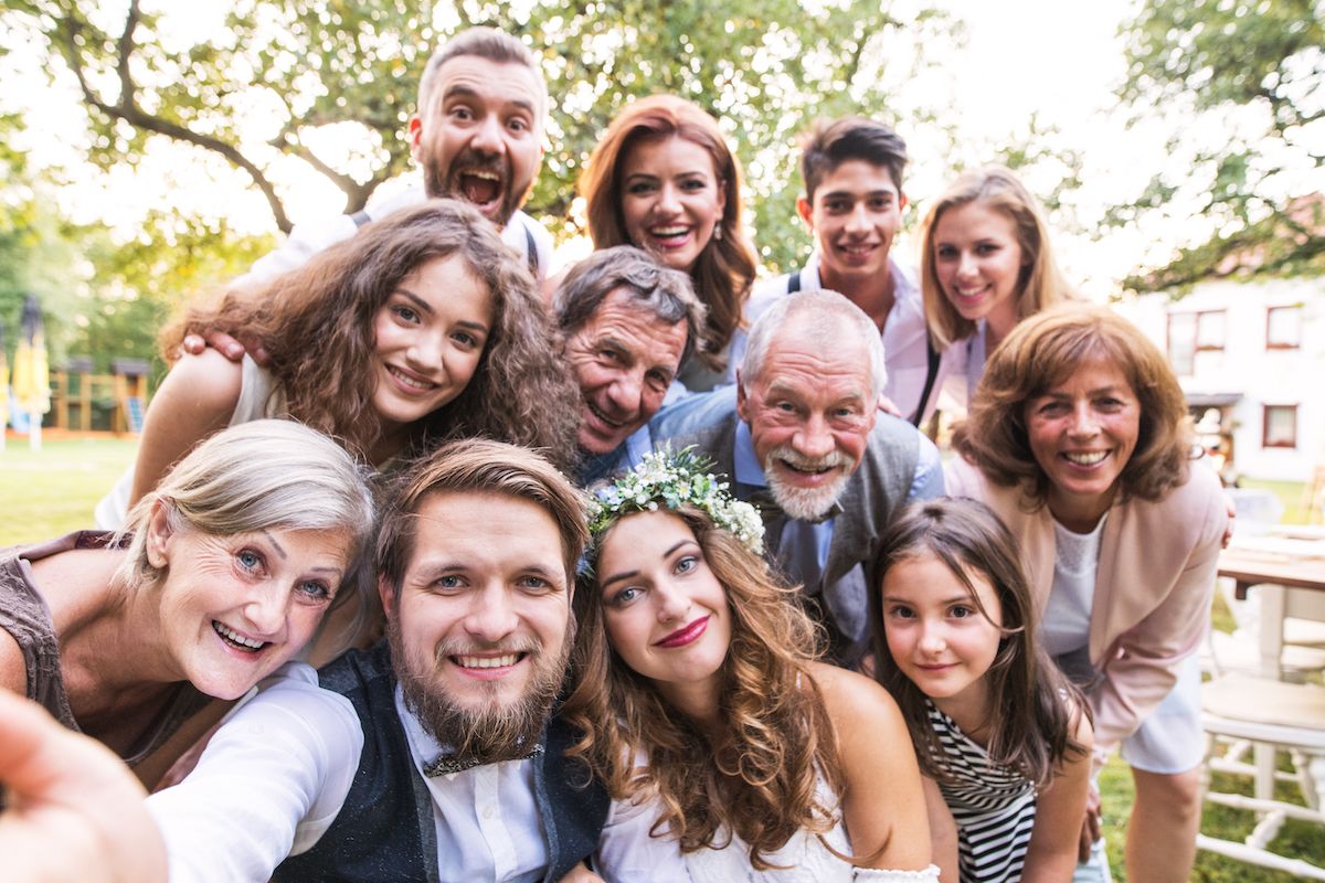 Eine Gruppe von Menschen, die bei einer Hochzeit ein Selfie machen.