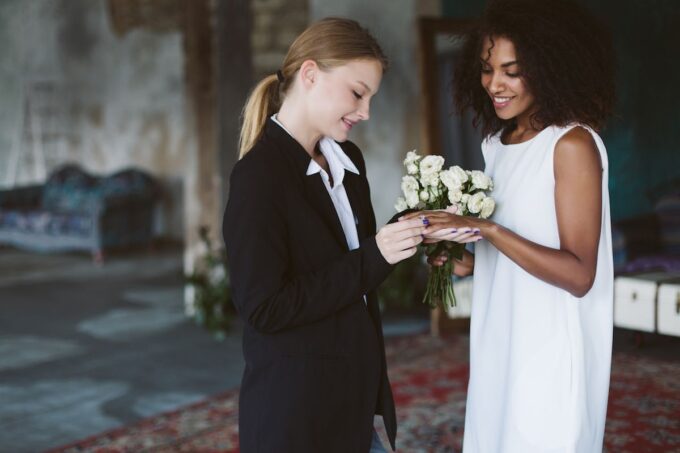 Eine Braut und eine Brautjungfer betrachten einen Blumenstrauß.