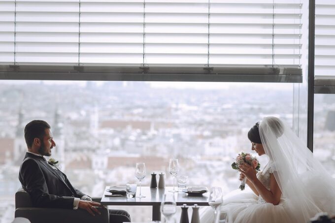 Ein Brautpaar sitzt an einem Tisch mit Blick auf die Stadt.
